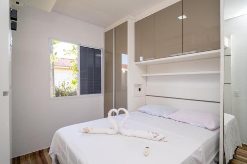 a bedroom with a bed with white sheets and a mirror at Rental Palhoça - Acomodações Residenciais IV in Palhoça