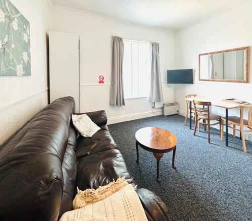 a living room with a leather couch and a table at Springfield Holiday Apartments HALodge Hotel in Skegness