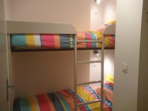 deux lits superposés dans une petite pièce avec des couvertures colorées dans l'établissement Apartment Brittany facing and seaside, à Plomodiern