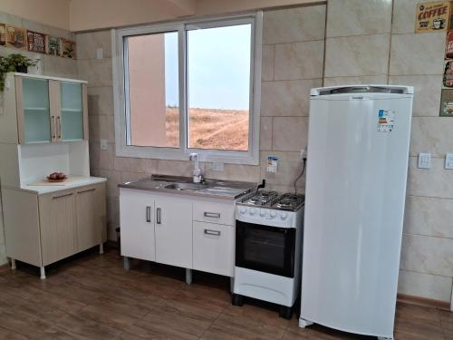 a kitchen with a stove and a sink and a window at Pousada Siriemas in Cambara do Sul