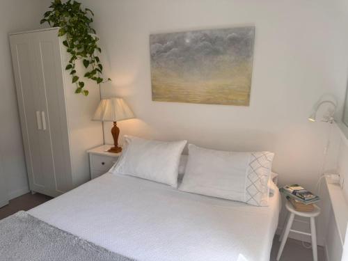 1 dormitorio con 1 cama con sábanas blancas y lámpara en Casa La Victoria, en Málaga