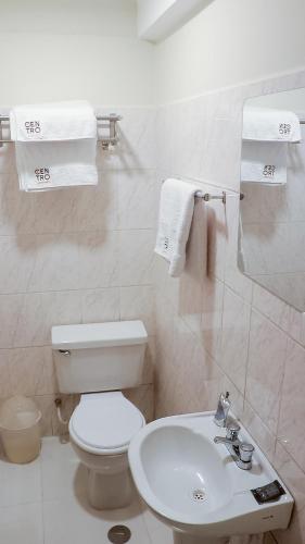 a bathroom with a toilet and a sink and towels at Hotel Centro Huancayo in Huancayo
