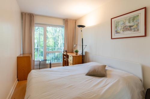 une chambre avec un lit blanc et une fenêtre dans l'établissement Escapade Courbevoie, à Courbevoie