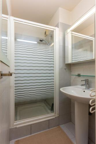 La salle de bains est pourvue d'une porte de douche en verre à côté d'un lavabo. dans l'établissement Escapade Courbevoie, à Courbevoie