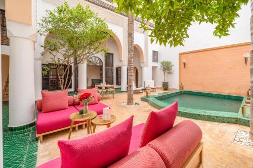 a courtyard with pink furniture and a pool at Riad Akasia in Marrakech