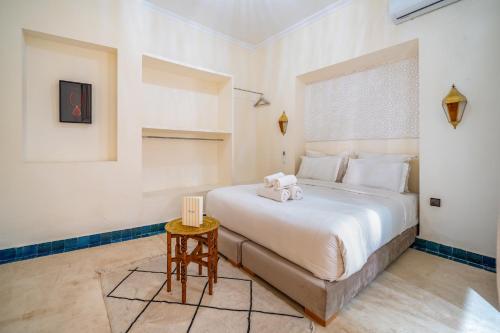 a bedroom with a large white bed and a table at Riad Akasia in Marrakech