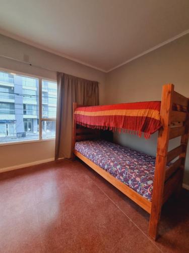 een slaapkamer met een stapelbed en een raam bij Guanaco Hostel in Puerto Madryn