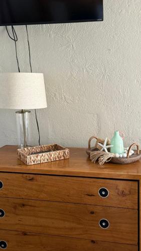 a wooden dresser with a lamp and a basket on it at Twin Palms Motel in Titusville