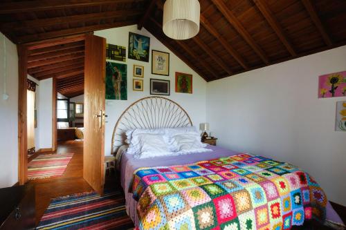 ein Schlafzimmer mit einem Bett mit einer bunten Steppdecke in der Unterkunft Casa do Lenho in Achadinha