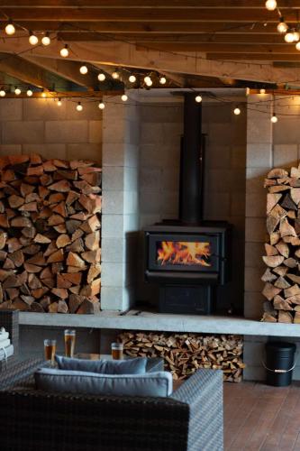 a fireplace with a stove in a room with logs at Inn Lewis - Beside the Redwoods with Spa Pool in Rotorua