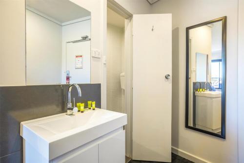 a bathroom with a white sink and a mirror at Nightcap at Rose & Crown Hotel in Elizabeth