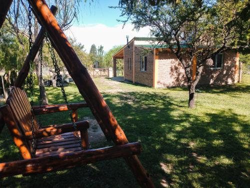 un columpio de madera en un patio con una casa en Cabañas Almafuerte, en Villa Quillinzo