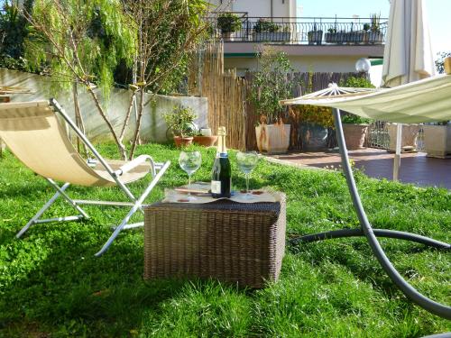 una mesa con una botella de vino, una silla y una sombrilla en Villa Bruna B&B, en San Remo