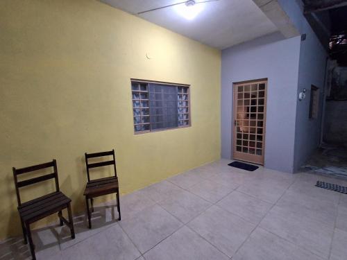 two chairs in a room with a yellow wall at Casa AMORA 2 quartos PISCINA in Aparecida