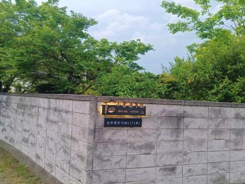 a sign on a concrete wall with trees in the background at 小景汤布院日式传统温泉民宿 in Yufuin