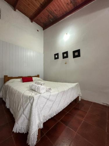 a bedroom with a bed with white sheets and a red pillow at Hospedaje La Terminal in La Porteña