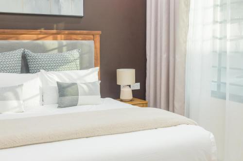 a bedroom with a white bed and a lamp at Naya at Meanwood in Lusaka