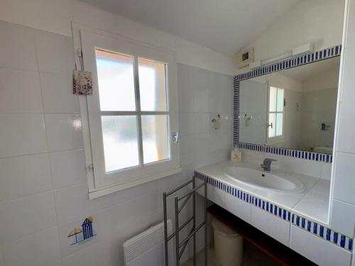 une salle de bain blanche avec un lavabo et un miroir dans l'établissement Maison charmante pour 6 pers. dans résidence calme avec piscine privée - FR-1-323-580, à Saint-Jean-de-Monts