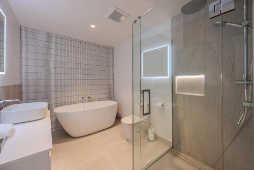 une salle de bain avec baignoire et douche en verre dans l'établissement Luxurious Townhouse Just Minutes From Lake Wanaka, à Wanaka