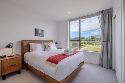 une chambre avec un lit et une grande fenêtre dans l'établissement Luxurious Townhouse Just Minutes From Lake Wanaka, à Wanaka