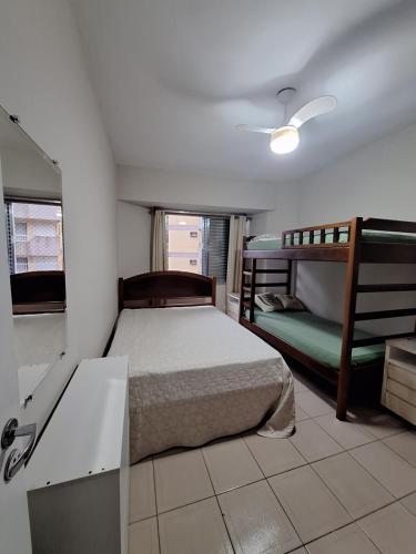 a bedroom with a bed and two bunk beds at Apartamento Guarujá Pitangueiras 50 metros Praia/3 Dormitórios/Vista do Mar, Sol da manhã in Guarujá
