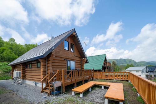 a log cabin with a wooden deck and a bench at Lake Toya Moon Hills in Lake Toya