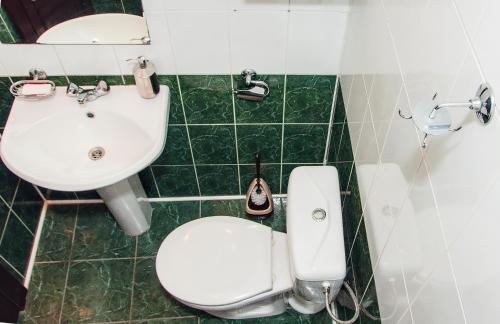 a green and white bathroom with a toilet and a sink at Globus Hostel in Kyiv