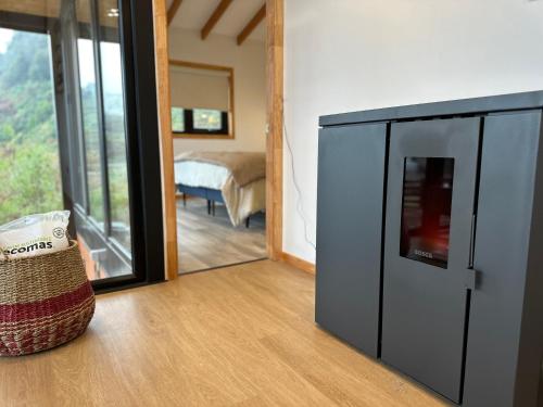 a room with a refrigerator and a bedroom with a bed at Moderna y acogedora casa estilo galpón in Puerto Aisén
