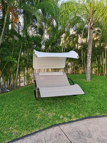 a white bench sitting in the grass with palm trees at Diana 28 in Jarretadera