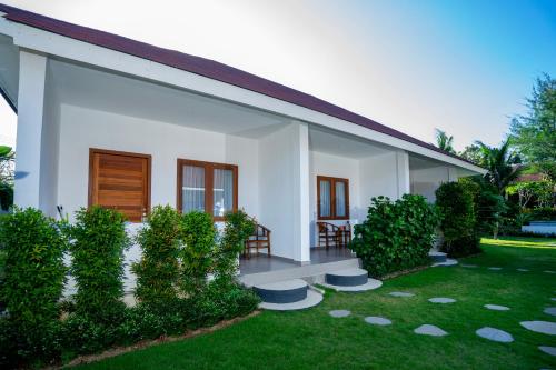 a white house with a lawn in front of it at Zena Surf Suite in Uluwatu