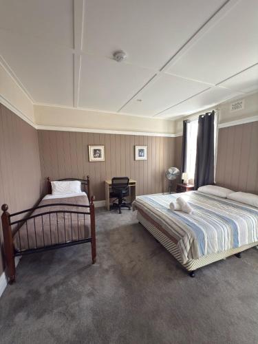 ein Schlafzimmer mit zwei Betten und einem Schreibtisch in der Unterkunft Apsley Arms hotel in Walcha