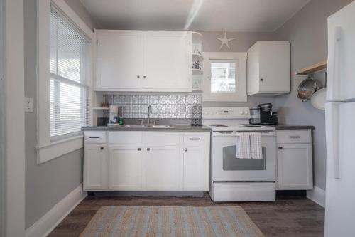 a kitchen with white cabinets and a stove top oven at Serene Beachy Bungalow with Large Screened Porch! in Tampa