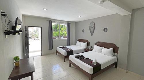 a hotel room with two beds and a table at Hotel Balxibá alberca y estacionamiento in Playa del Carmen