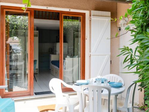 une table blanche et des chaises sur une terrasse dans l'établissement Pavillon Studio Mezzanine Climatisé Proche Plage avec Parking - FR-1-409A-37, à Gruissan