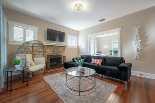 a living room with a black couch and a fireplace at Historic & Cozy Bungalow by Downtown in Tampa