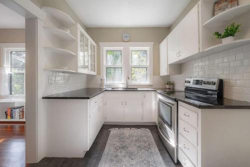 a kitchen with white cabinets and black counter tops at Historic & Cozy Bungalow by Downtown in Tampa