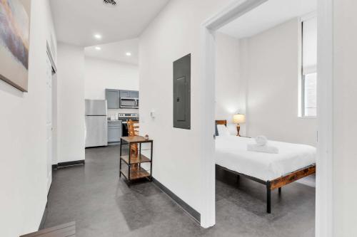a white bedroom with a bed and a kitchen at CozySuites Modern 1BR in Downtown Pitts #22 in Pittsburgh