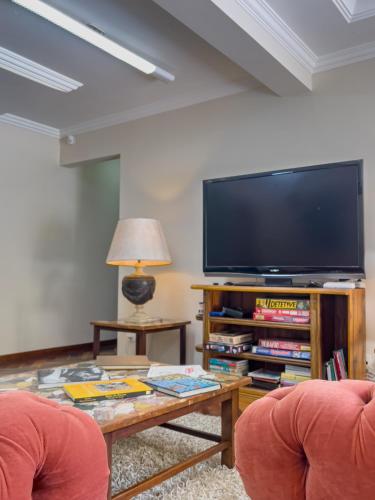 a living room with two chairs and a large television at Araucária Lodge - 800 metros do Capivari in Campos do Jordão