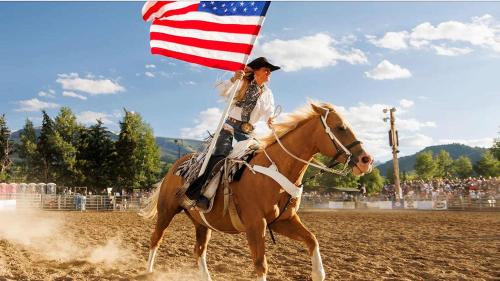 a woman riding a horse holding an american flag at 2 BR 3BA Condo - AC, Heated Pool, Walk to Town in Aspen