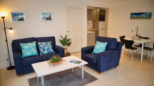 a living room with two blue chairs and a table at Blueys Apartment @ 192 Boomerang Drive in Blueys Beach