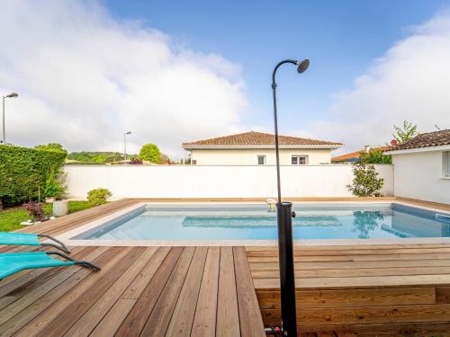 une piscine avec une terrasse en bois et une maison dans l'établissement Maison à Mimizan avec jardin et piscine privée pour 6 personnes - FR-1-50-95, à Mimizan