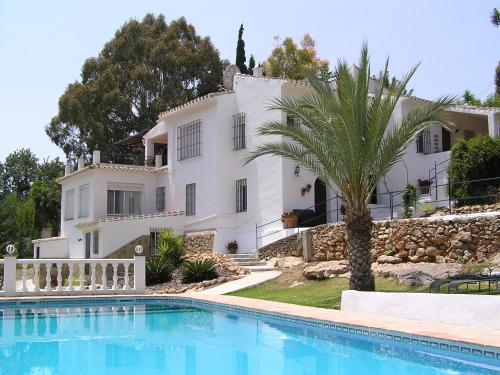 a large white house with a palm tree and a swimming pool at Villa Morera Bed & Breakfast in Frigiliana