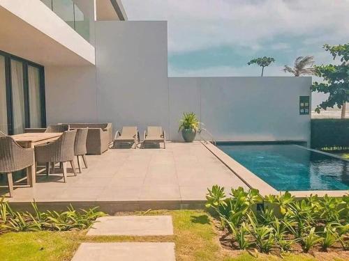 a house with a swimming pool and a table and chairs at SANCTUARY HỒ TRÀM RESORT - Near beach in Ho Tram