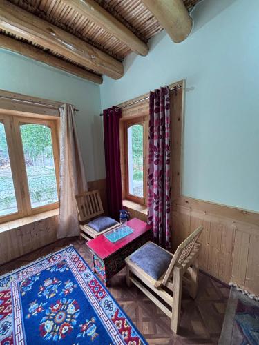 a living room with a table and chairs and windows at KARMA Homestay Sumur Nubra in Nubra