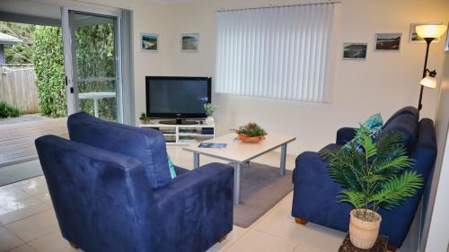 a living room with blue chairs and a tv at Blueys Apartment @ 192 Boomerang Drive in Blueys Beach