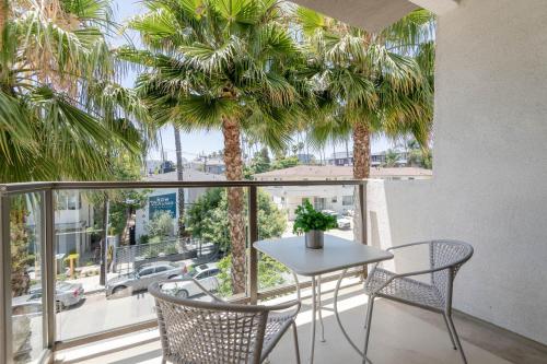 a table and chairs on a balcony with palm trees at Hollywood Cozy Apartment in Los Angeles