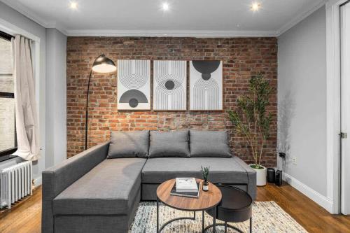 a living room with a couch and a brick wall at Modern Manhattan Retreat Near Central Park in New York