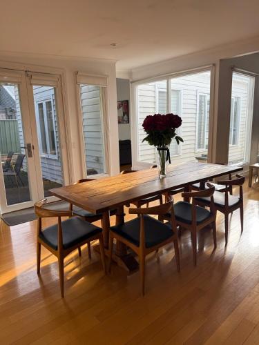 a dining room table with chairs and a vase of flowers at Spacious self contained house walking distance-CBD in Bendigo