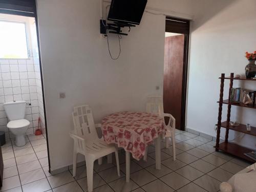 a kitchen with a table and chairs and a tv on the wall at Chez Janou (sci sijimad) in Sainte-Anne