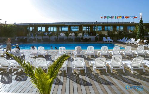 a group of white chairs and a swimming pool at Vitrali in Caldera